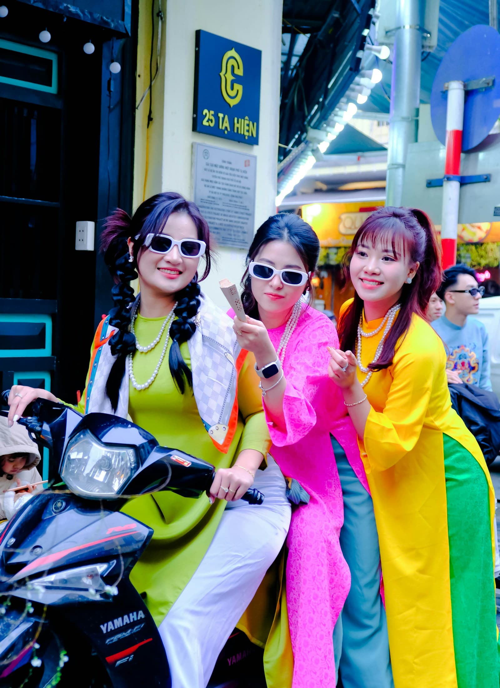 Three women posing beside a motorbike