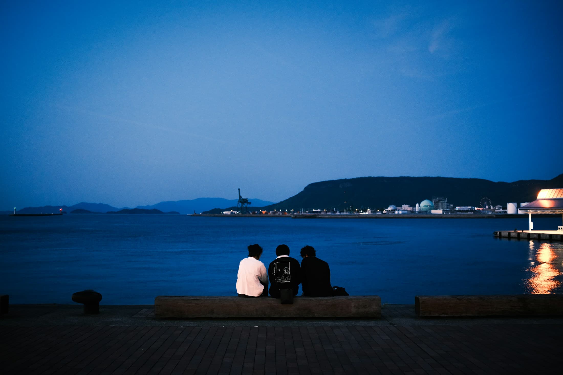 Three friends relaxing by the waterfront at night